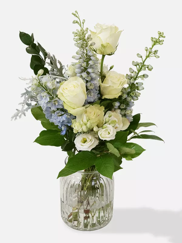 Bouquet of Athena White roses with Delphinium and Lisianthus in a clear glass vase.
