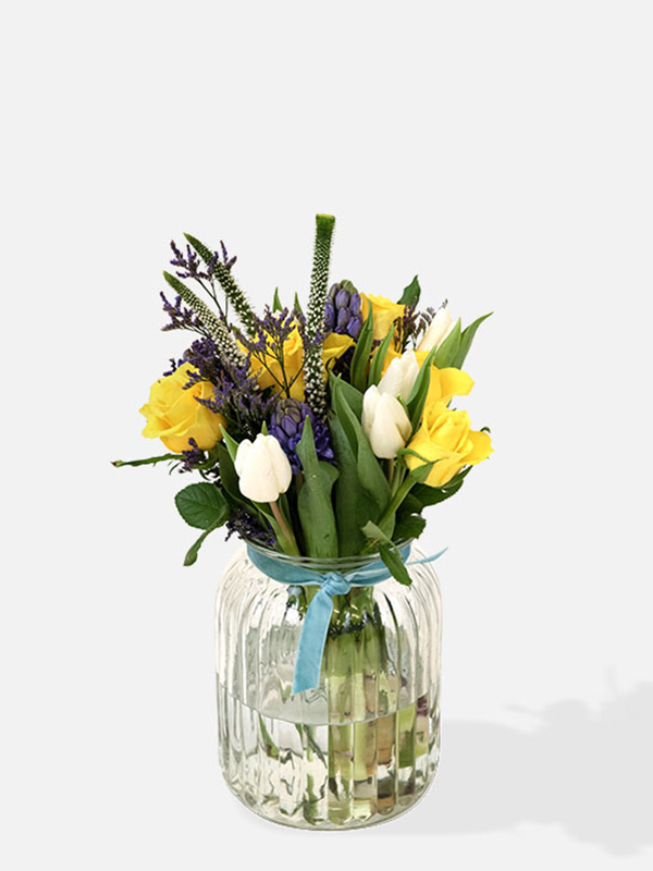 Bouquet of yellow roses, white tulips, purple hyacinth and limonium in a vase